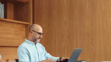 Man sitting at desk using laptop