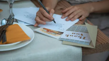 Hands signing a a thank you card