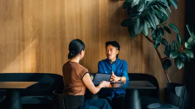 Man sitting across from woman who has laptop in front of her