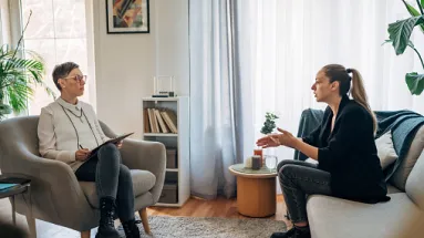 A woman on a couch talking to her therapist who is sitting in a chair 