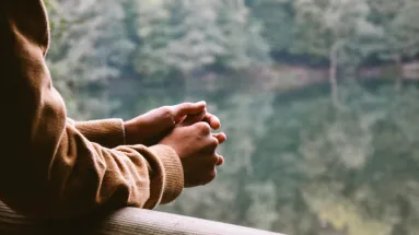 person leaning on banister staring at nature 