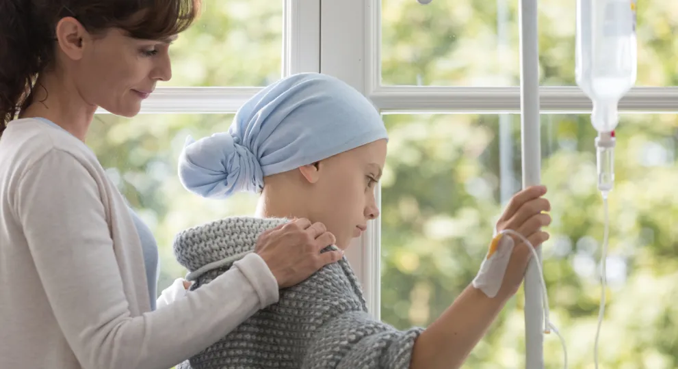 Mother comforts child with cancer receiving IV treatment 