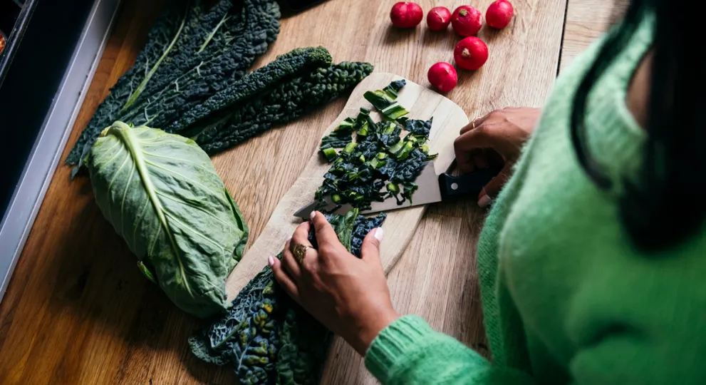 woman cutting vegetables on wooden cutting board 
