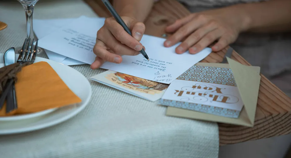 Hands signing a a thank you card