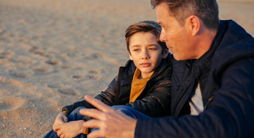 father and son sitting on the sand during the spring